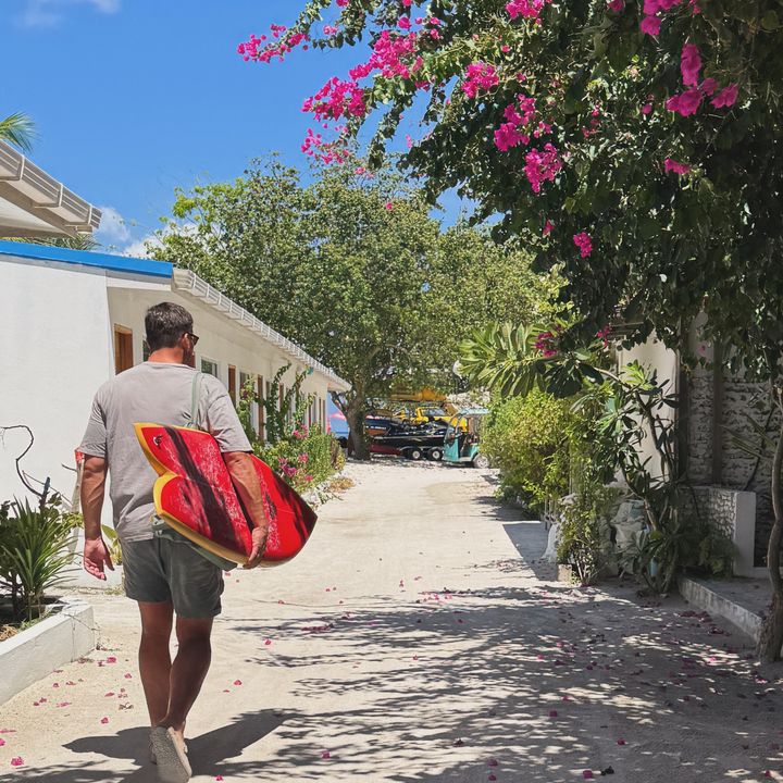 Guy Vero walking to the beach with a board under his arm